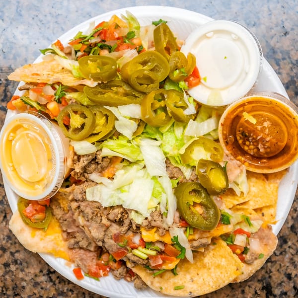 A plate of Cesar's Tacos!!! nachos with meat, cheese, lettuce, pico de gallo, and jalapeños.